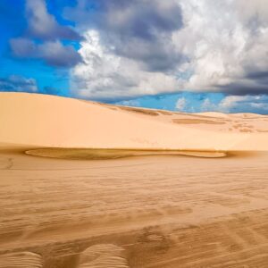 Explore the vast sand dunes of Maranhão, Brazil, set against a backdrop of dramatic, cloudy skies.