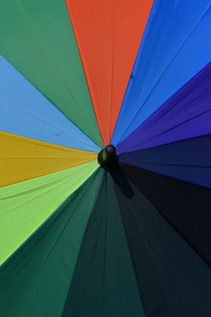 Colorful umbrella with rainbow panels viewed from above, showcasing vivid hues.