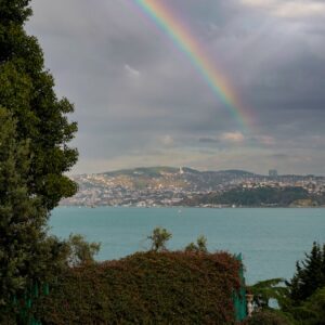 Stunning rainbow arches over a scenic seaside city view.
