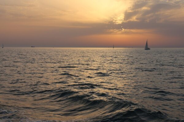 Sailboats drift peacefully on a serene sunset bay in Andalucía, Spain.